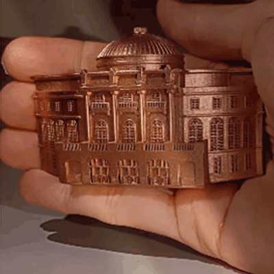 3D Magnet des Chemnitzer Opernhauses in bronzefarbener Miniatur, gehalten in einer Hand zur Größenansicht.