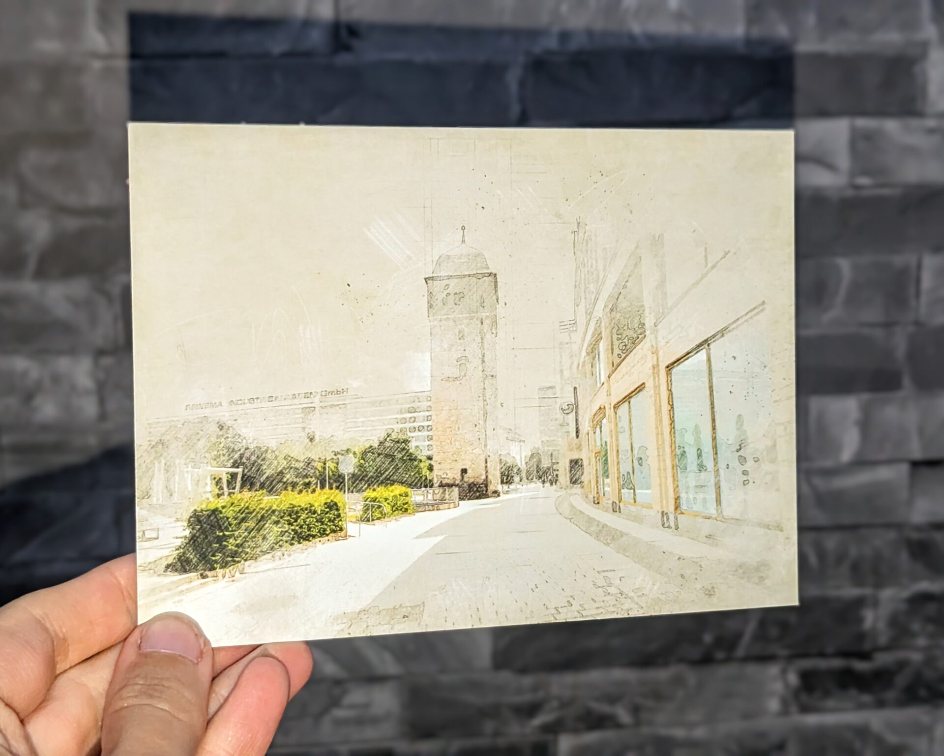 Künstlerische Postkarte mit dem Roten Turm in Chemnitz, im sanften Vintage-Zeichenstil gestaltet, gehalten vor einer grauen Steinwand. Das Motiv zeigt den historischen Turm sowie angrenzende Gebäude und Grünflächen.