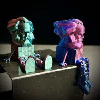 Bewegliche Karl-Marx-Figur aus Chemnitz mit Armen und baumelnden Beinen in Farbverlauf Grün-Lila-Blau – modernes Merchandise-Geschenk.